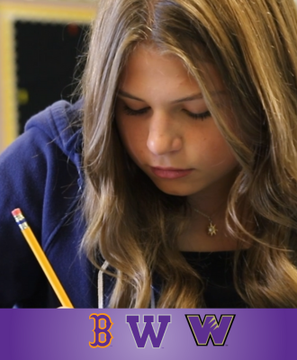  Walnut 8th Grade student (girl) writing on a paper with a pencil at her classroom desk.