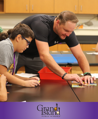  Barr Middle School science teacher working with 6th Grade students at a desk. 