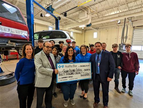 GISH Automotive students standing with Healthy Blue Team, Sen. Aguilar, and Principal D. W. Holley w/ big check.