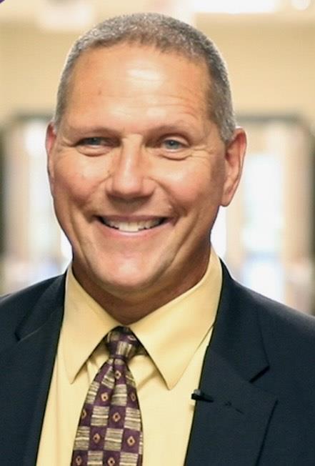 Mr. Matt Fisher in suit and tie smiling in a school hallway