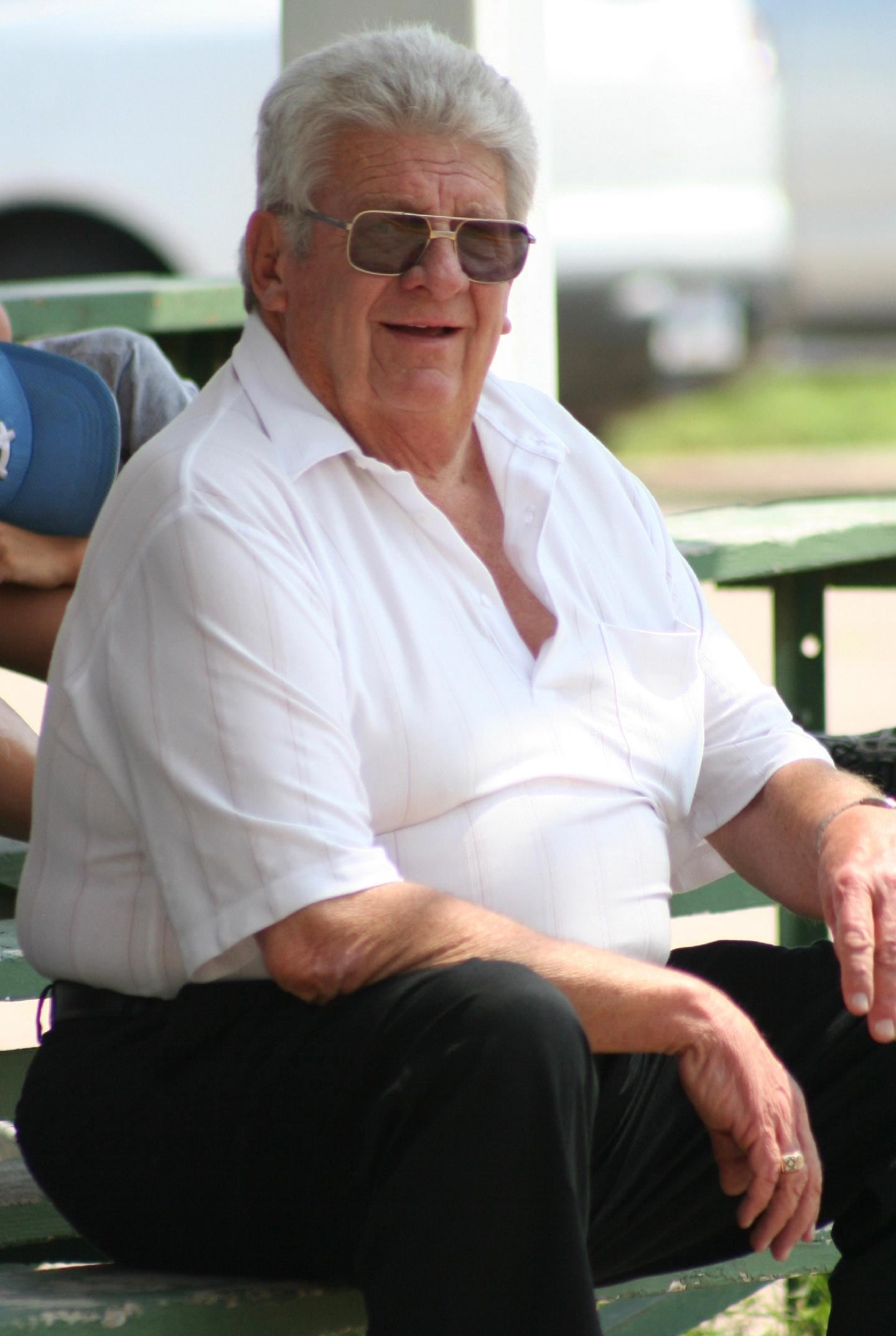 Jerry Henke enjoying a ball game wearing sunglasses, white polo, and black slacks.